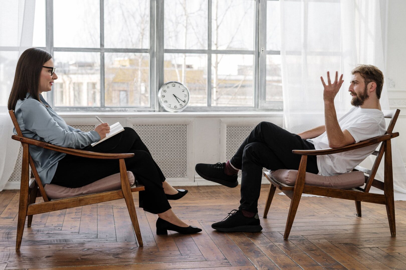 Two people sitting in chairs on a wooden floor